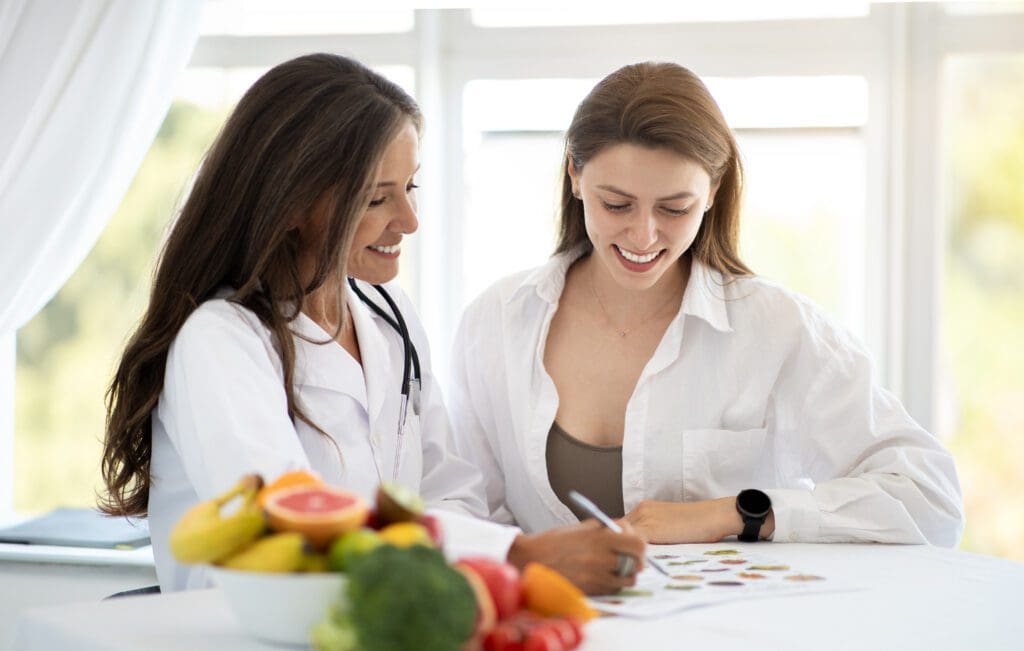 Two women sitting at a table with fruit.