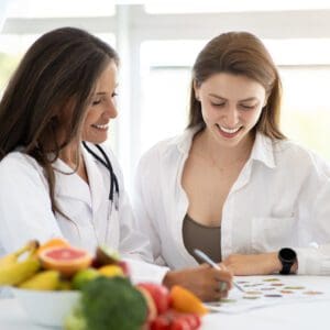 Two women sitting at a table with fruit.