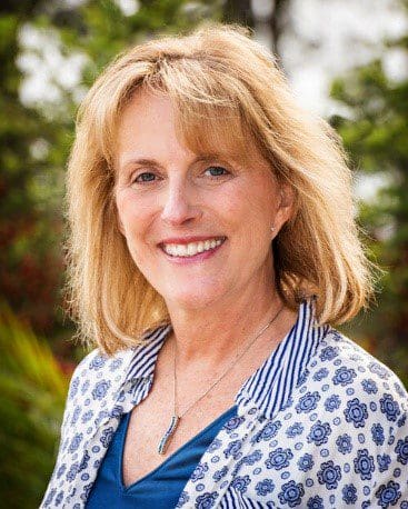 Woman smiling outdoors with floral shirt.