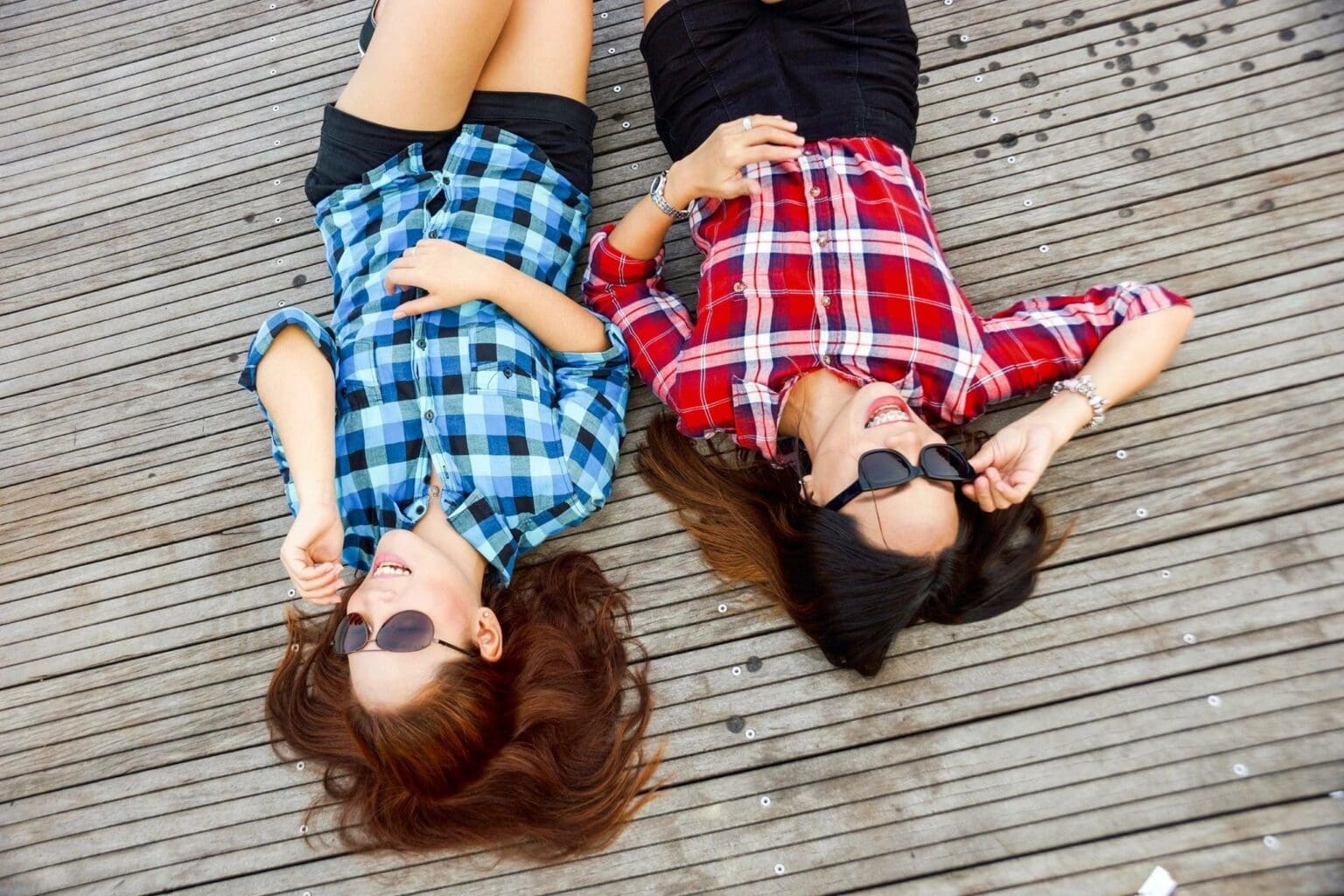 Two women in plaid shirts lying outdoors.