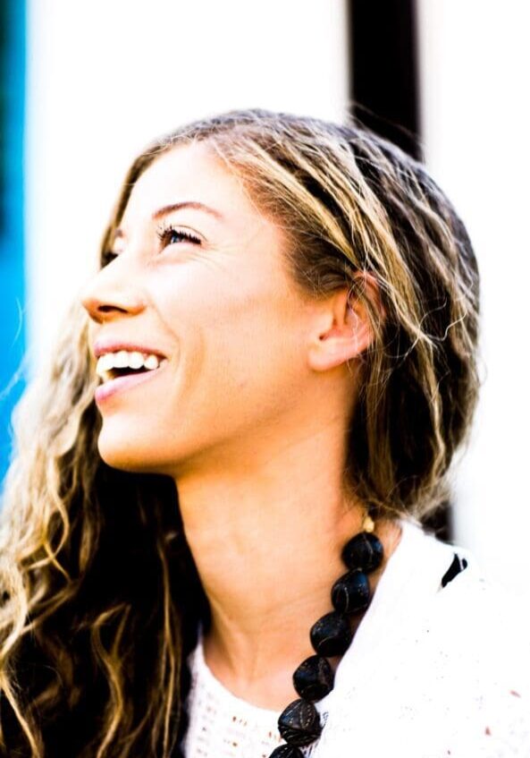 Smiling woman with wavy hair and necklace.