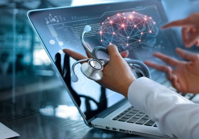 Doctor using laptop with digital brain hologram.